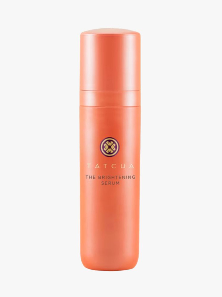 Orange bottle of Tatcha The Brightening Serum on a light gray background